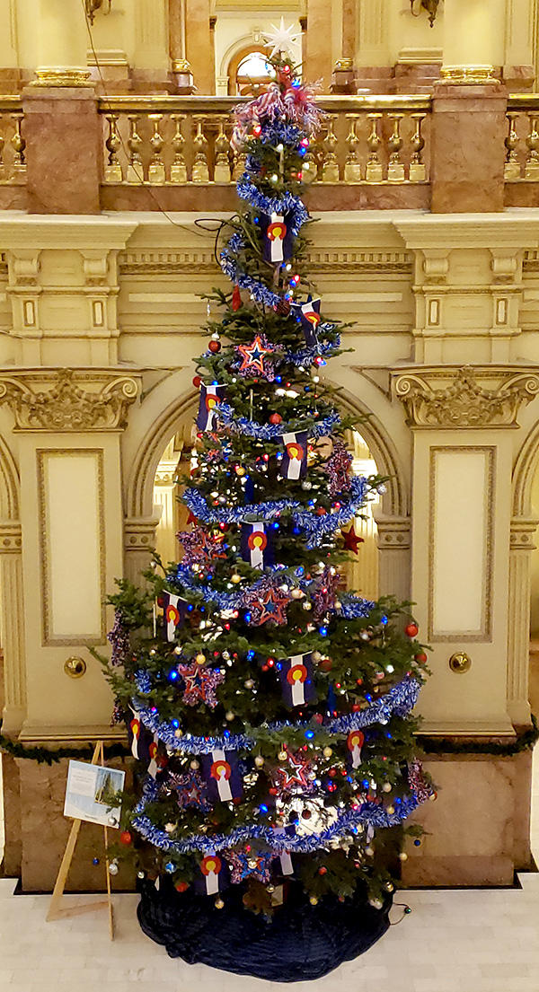A decorated holiday tree as tall as the second story balcony inside a rotunda at the Capitol building.